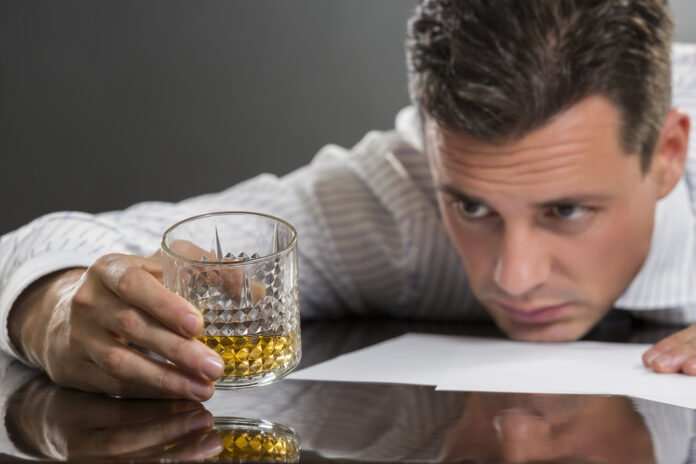 Wanneer Ben Je Alcoholist? Symptomen die je niet mag negeren. Deze man op de afbeelding drinkt en vraagt zich af of het tijd is om te stoppen.