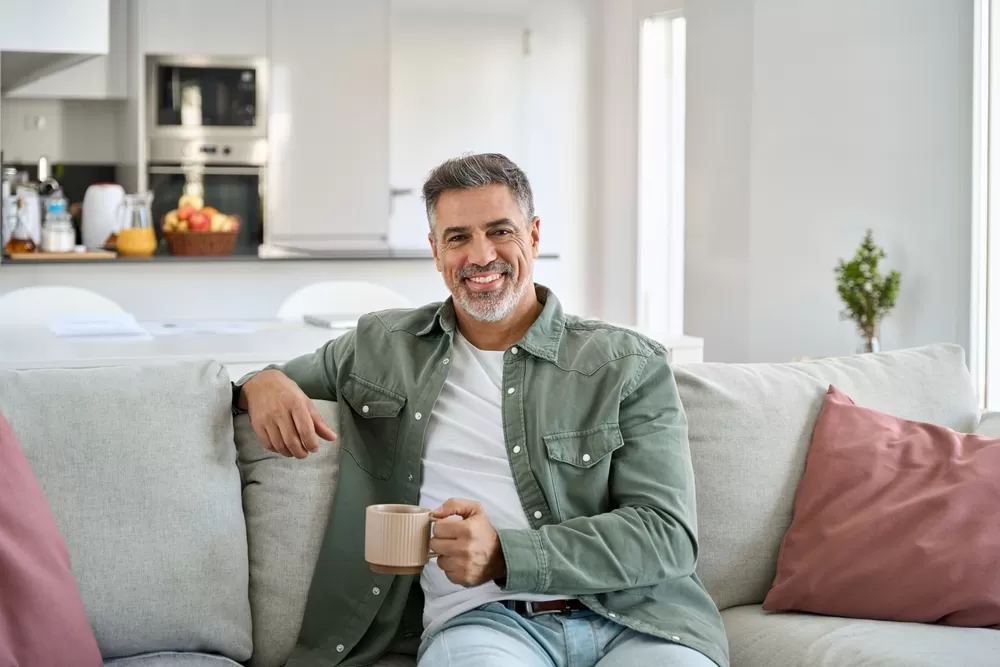 Man die ontspannen thuis op de bank zit met een kop koffie
